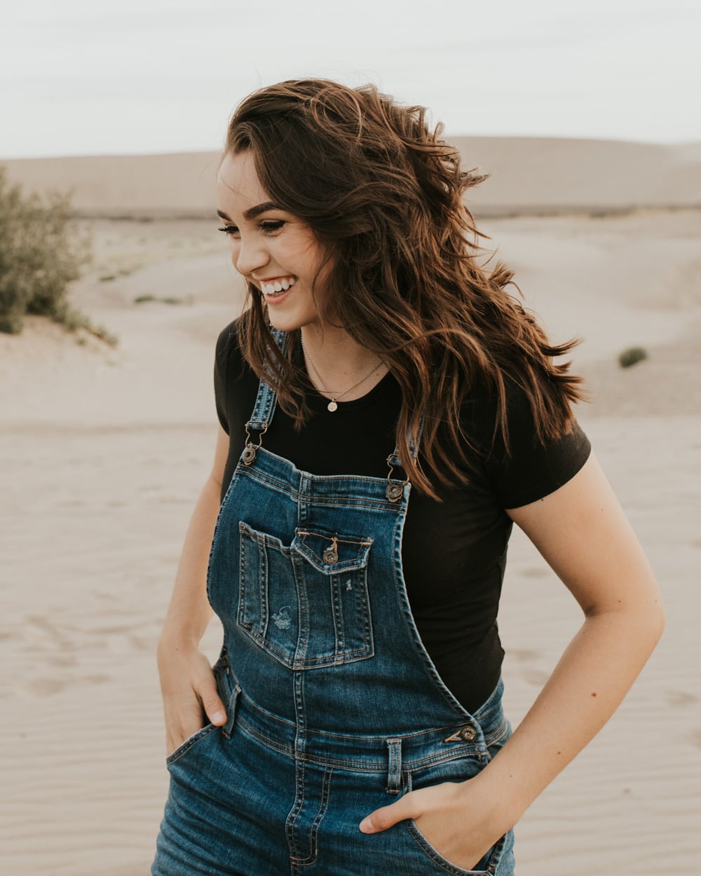 A girl smiling at the ground at the Saint Anthony Sand Dunes in Idaho.