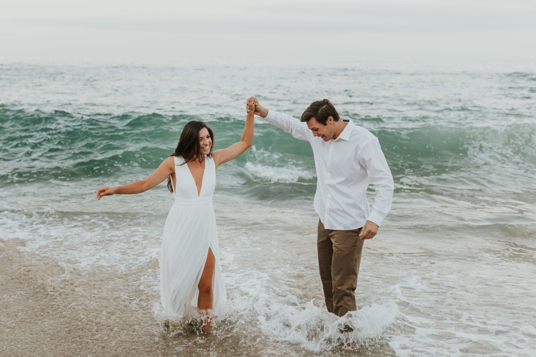 A bride and groom playing in the water on their elopement day.
