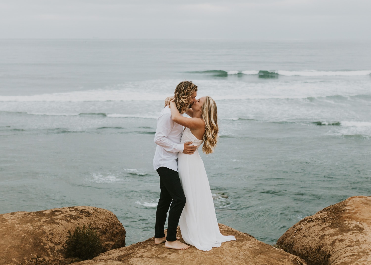 A bride and groom hugging at Sunset Cliffs Natural Park in San Diego, California during their sunrise elopement.
