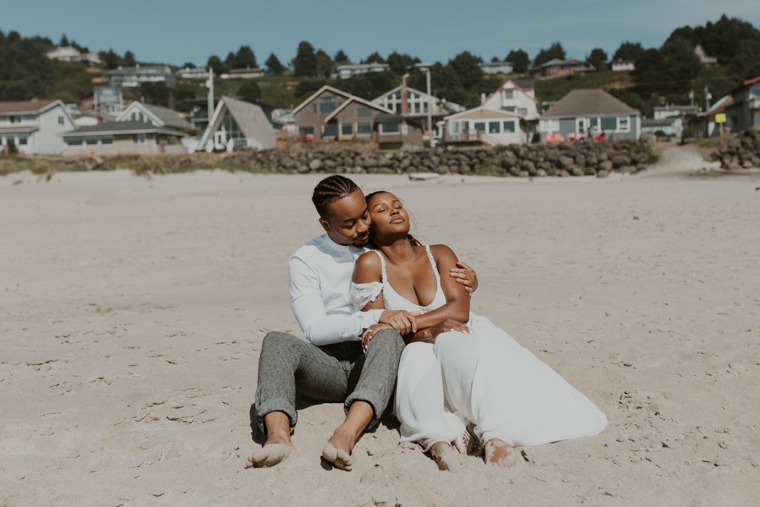 A bride and groom snuggling on a beach in California for their elopement.