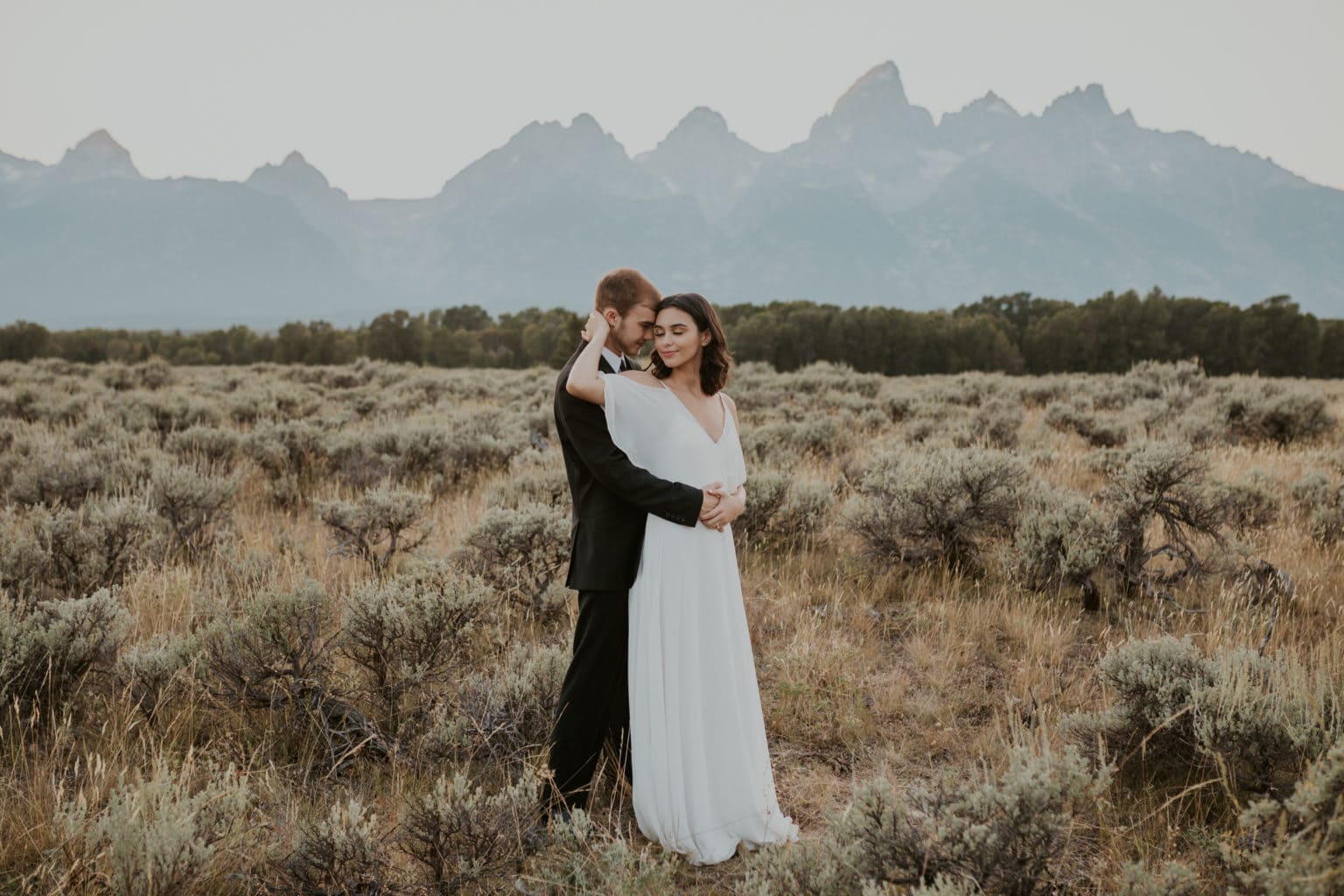 A bride and groom hugging in front of mountains, captured by Brianna Parks, a California elopement photographer.