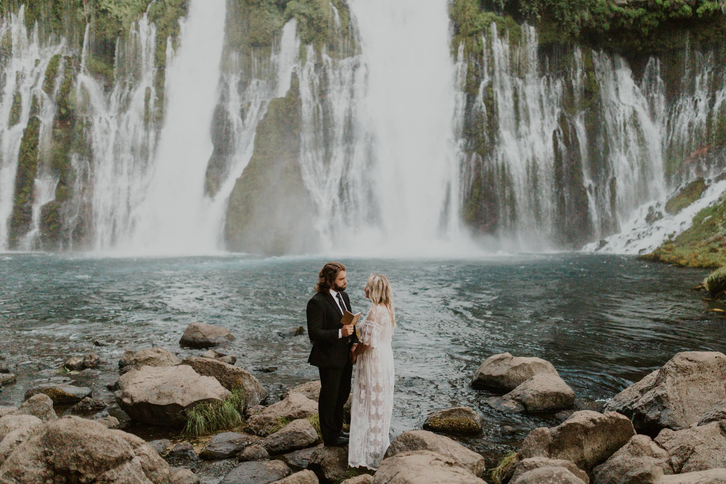 A groom reading his vows in front of a waterfall on the couples wedding day.