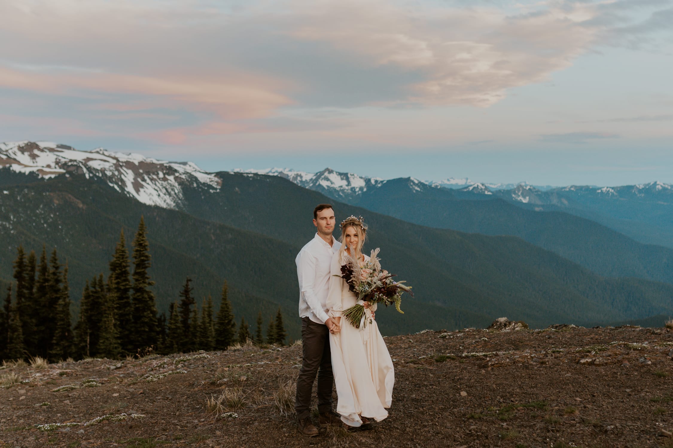A bride and groom smiling at the camera on Hurricane Ridge in Washington State.