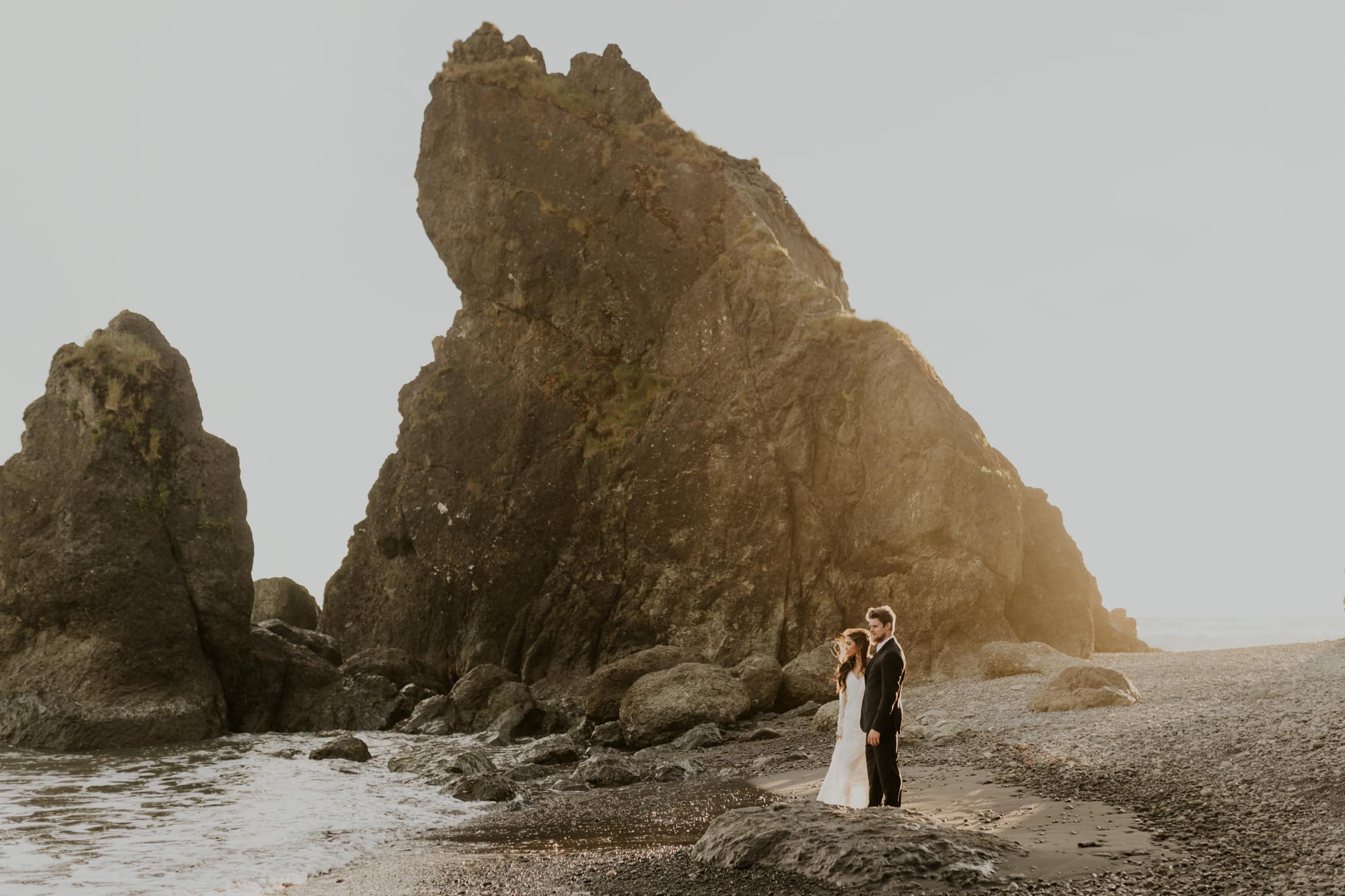 A bride and groom looking out at the ocean on Ruby Beach in Olympic National Park.