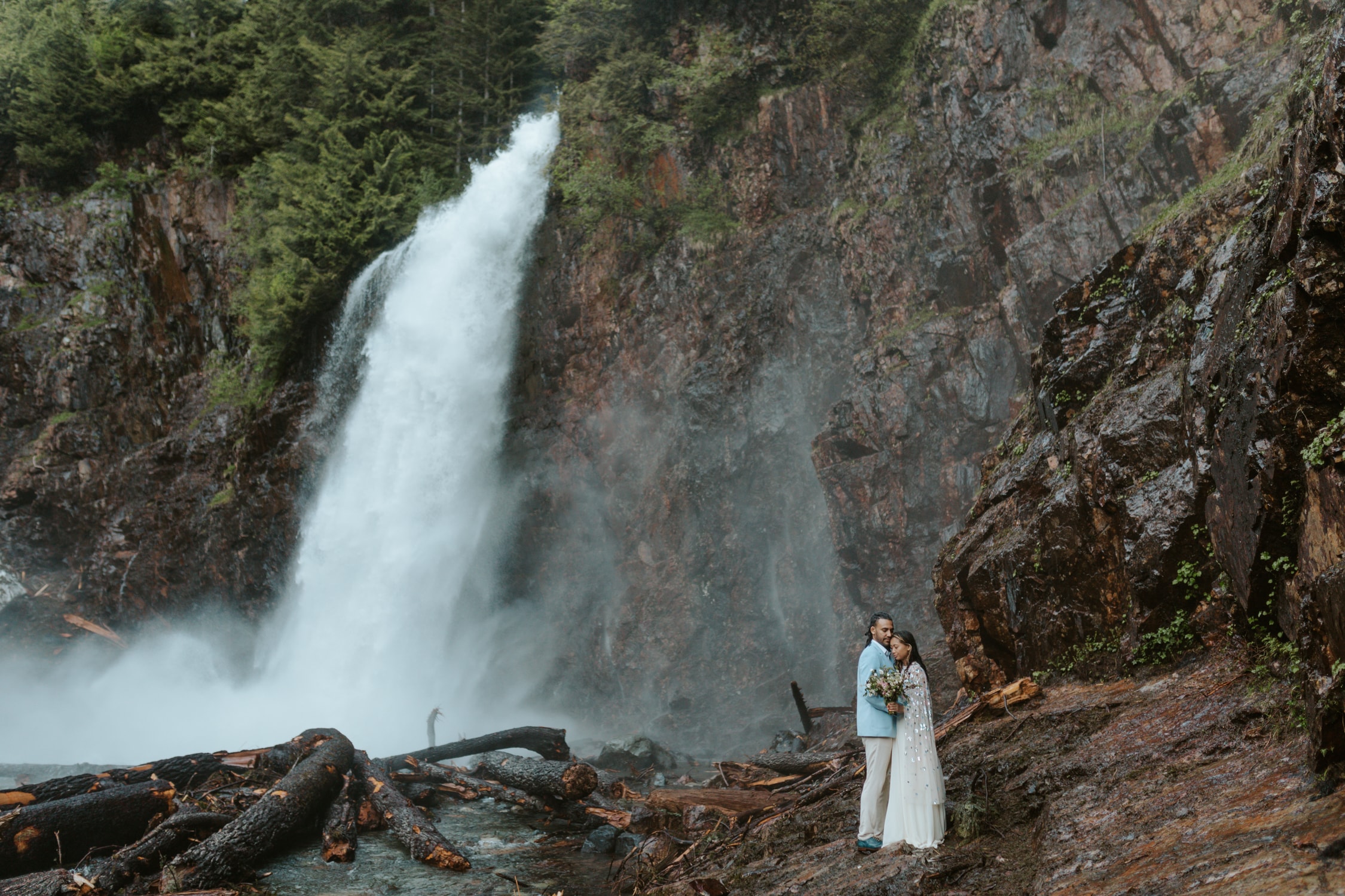 A bride and groom hugging each other next to Franklin Falls in Washington.