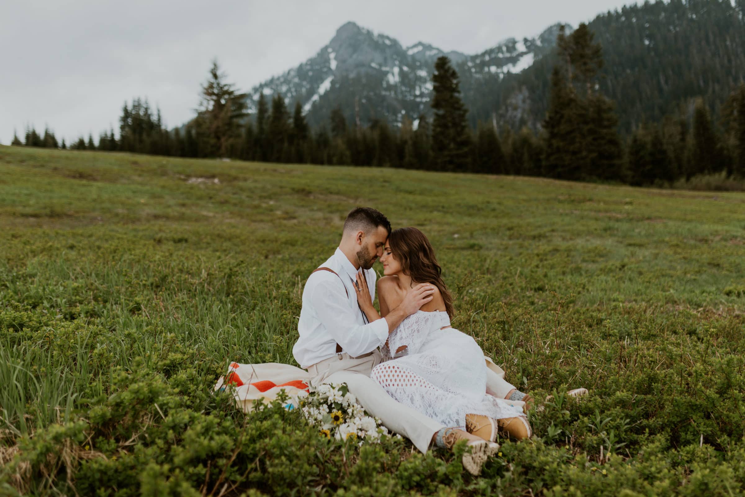 A bride and groom snuggling in front of a mountain on their wedding day.