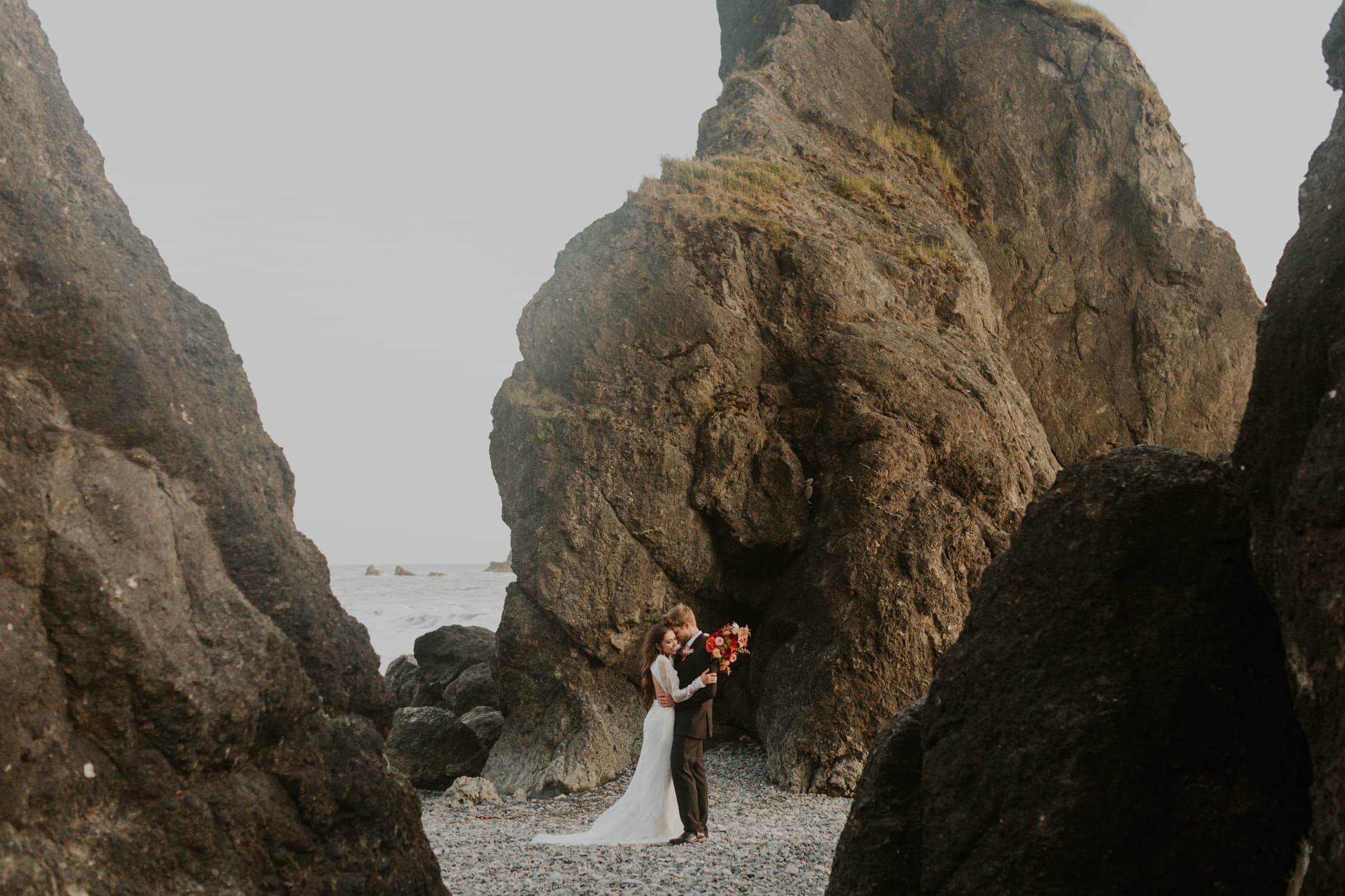 A bride and groom hugging each other on Ruby Beach in Olympic National Park.