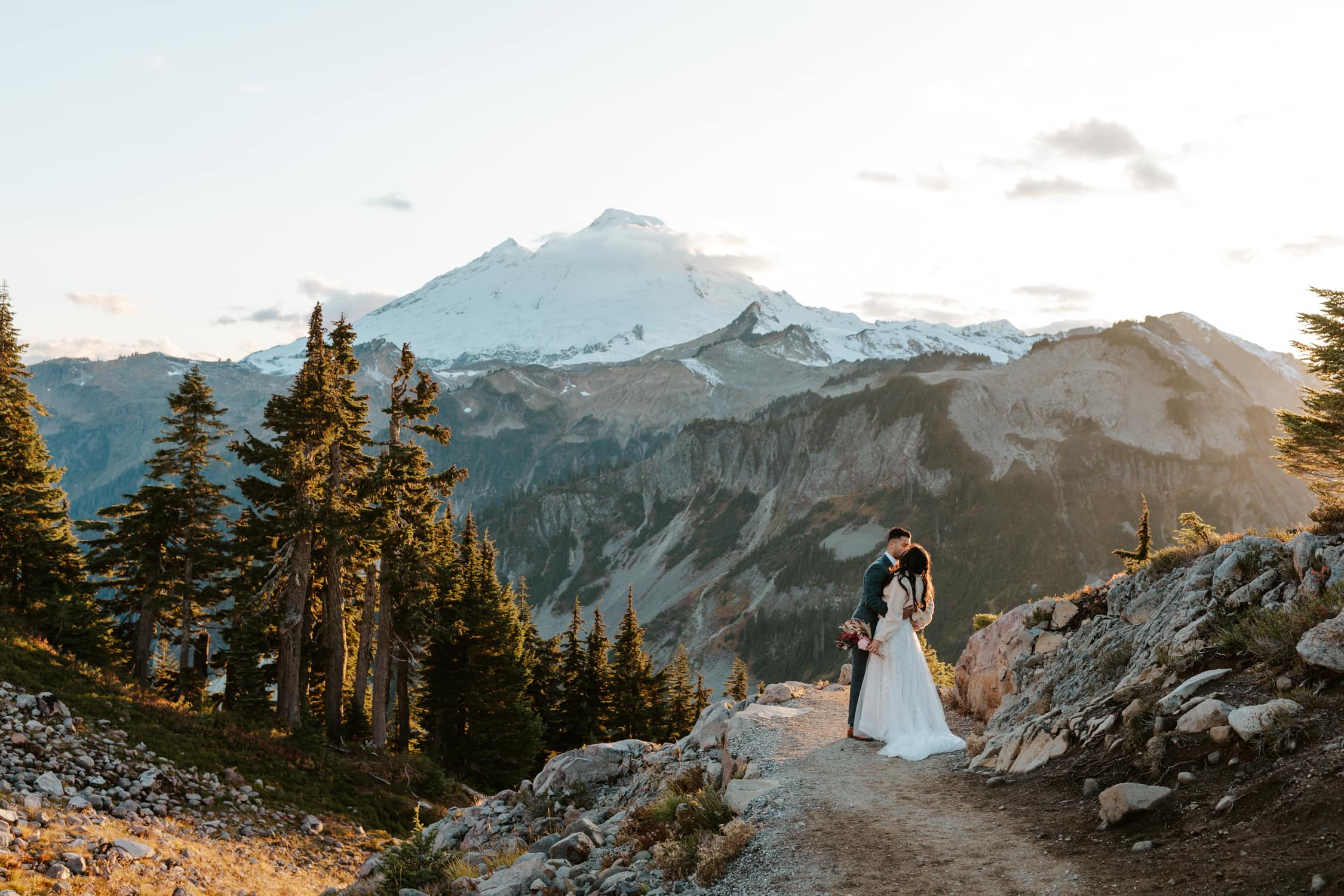 A couple in wedding attire kissing in front of Mt. Baker.