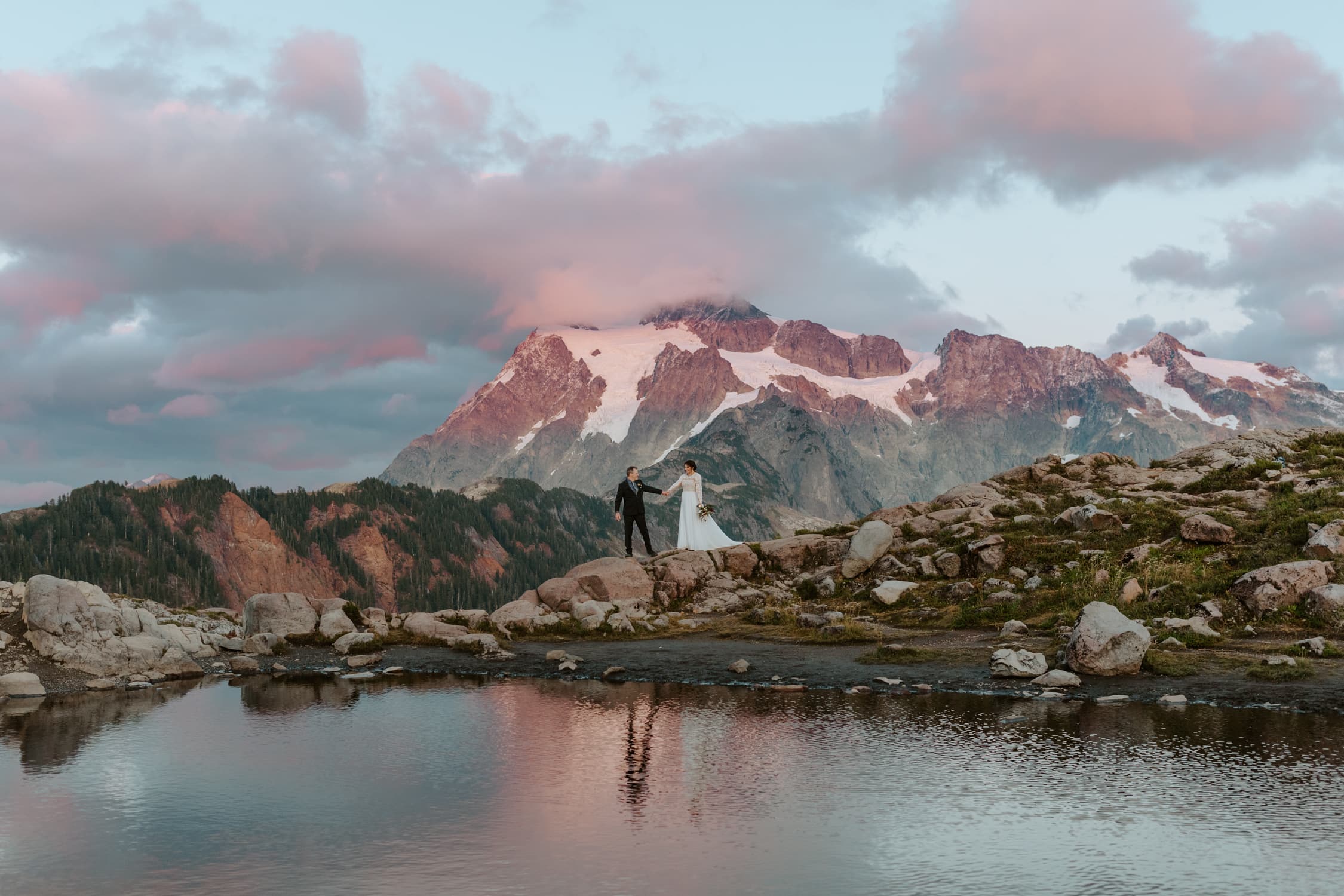 A couple in wedding attire walking along some rocks at Artist Point in the North Cascades.