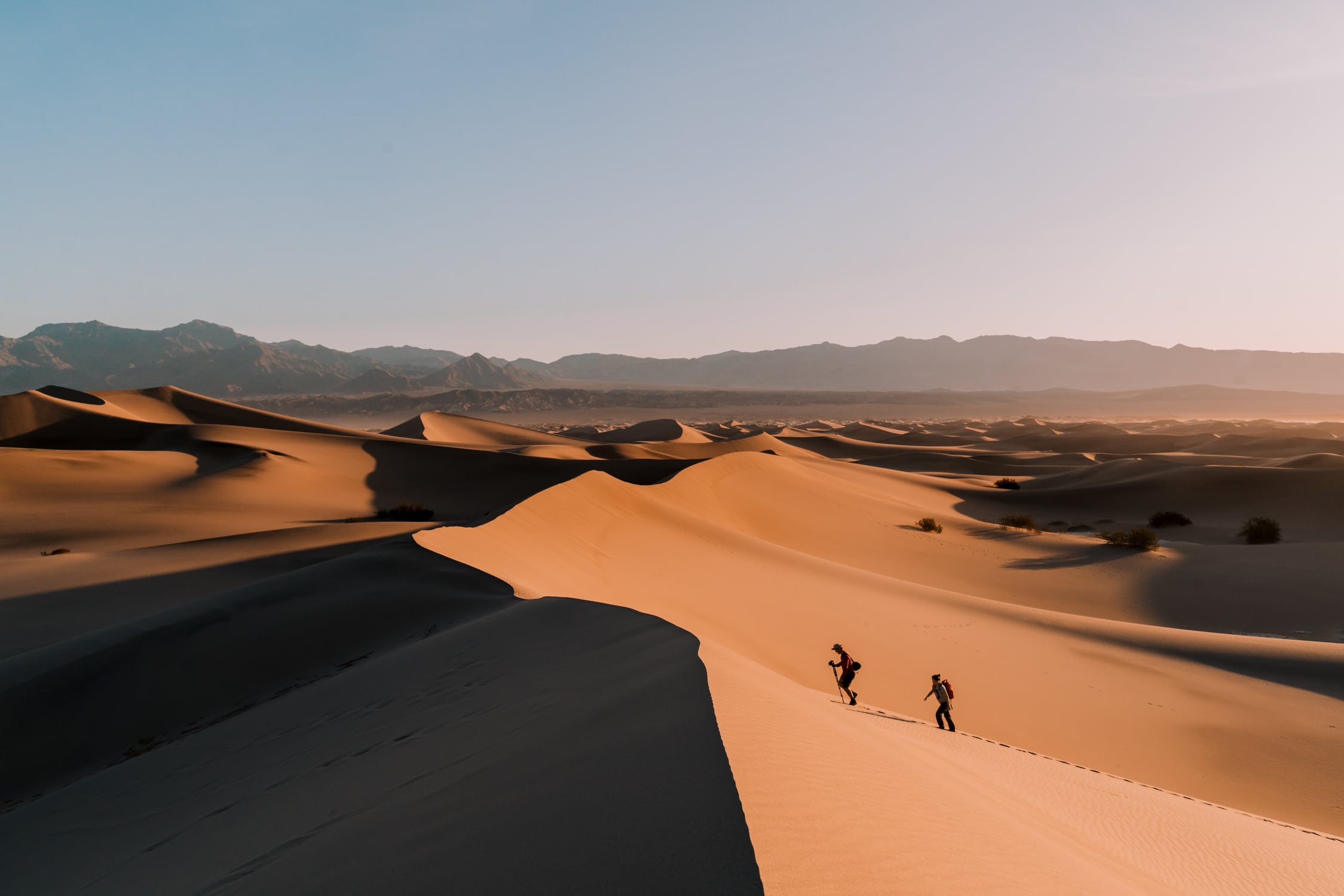 Two people hiking in the Mesquite Flat Sand Dunes in Death Valley National Park.