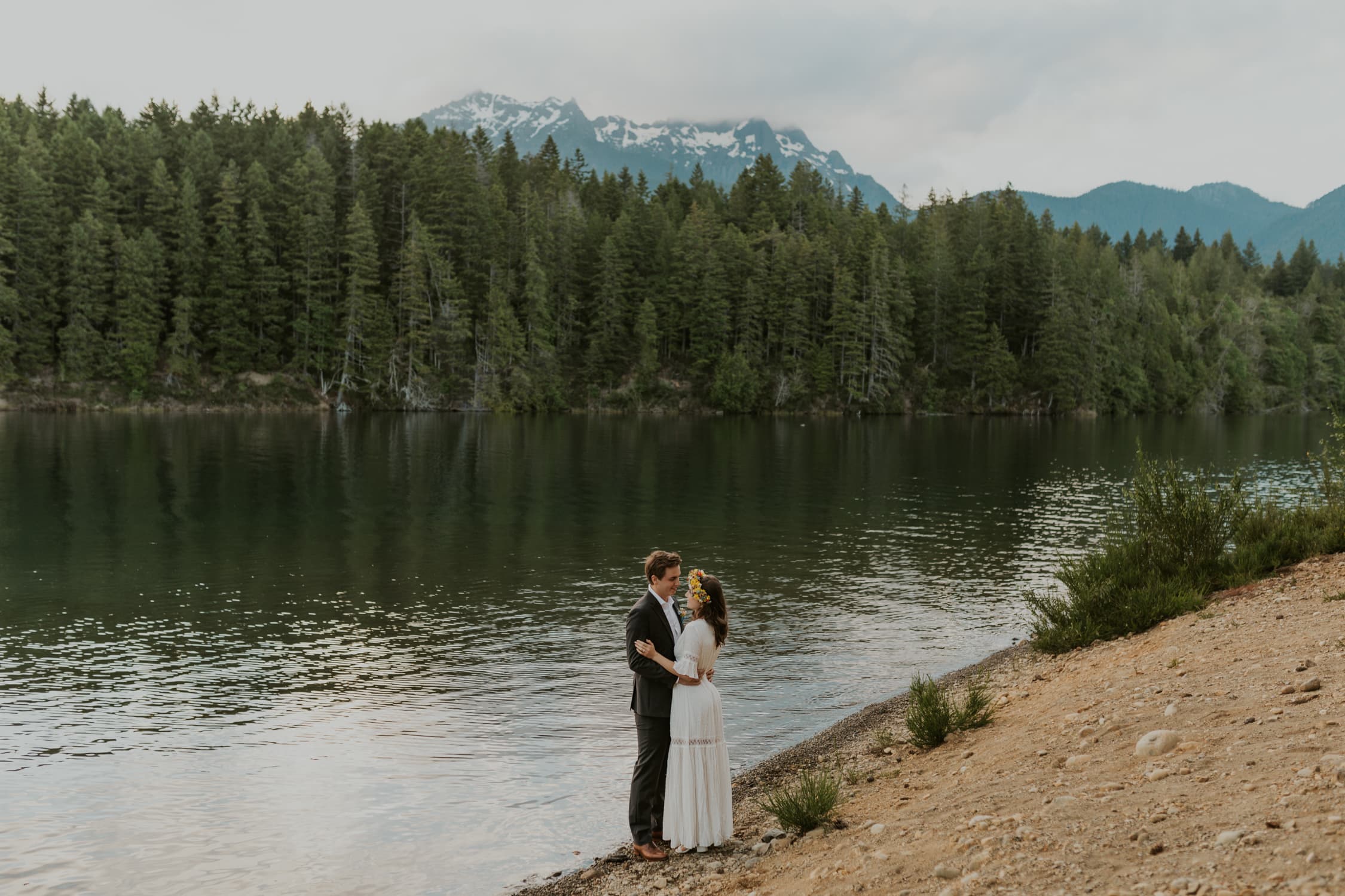 A bride and groom facing each other at Lake Cushman during their elopement.