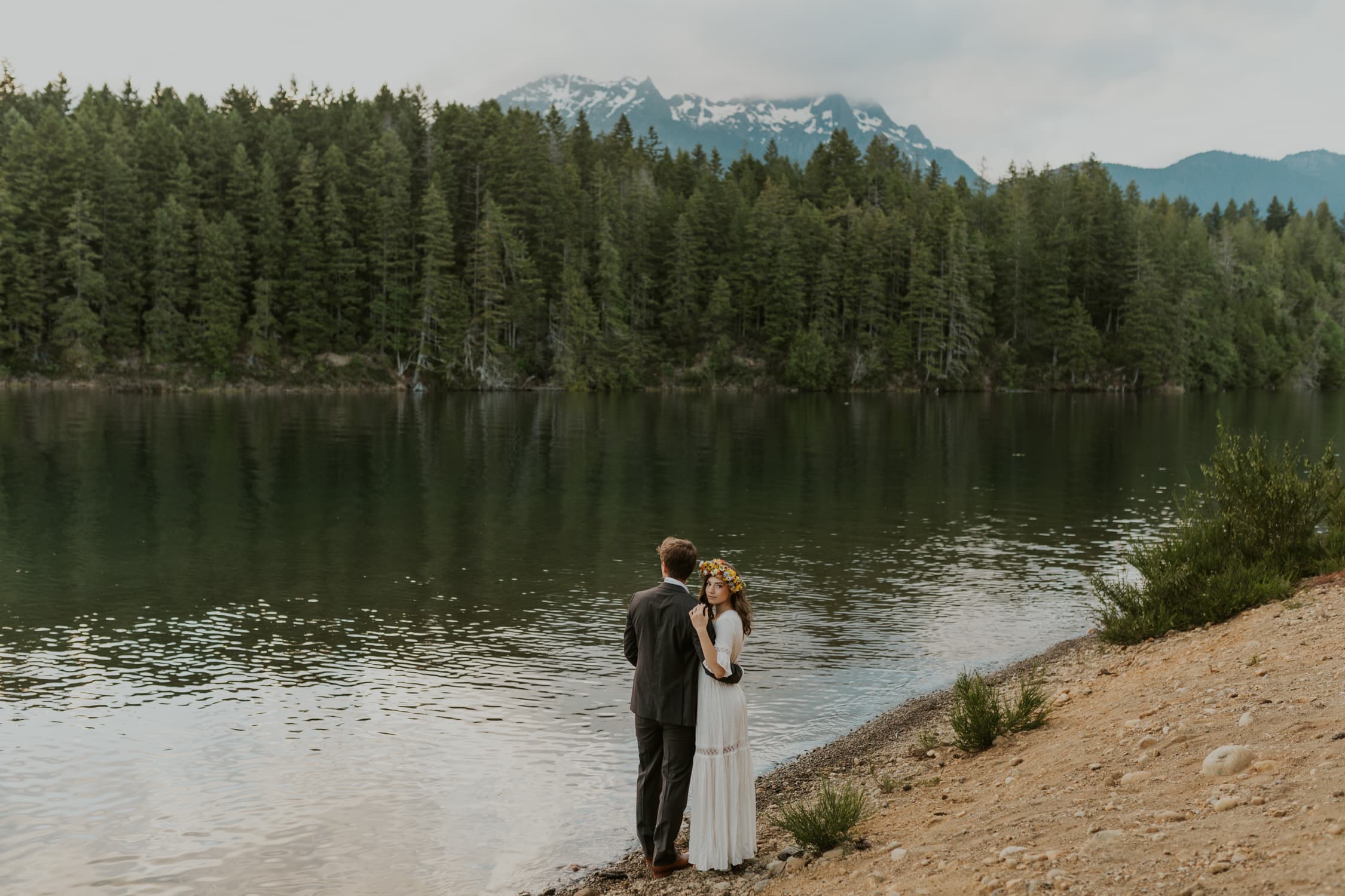 A bride facing the camera in front of Lake Cushman.