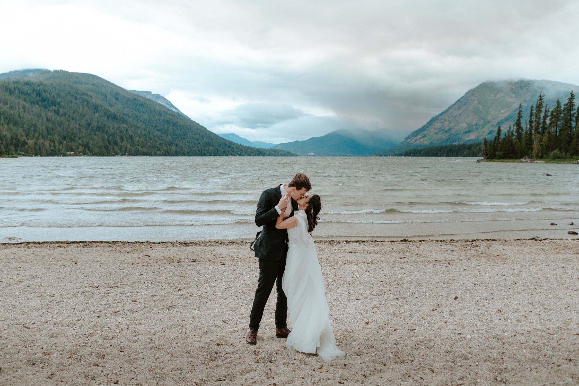 A couple in wedding attire kissing at Lake Wenatchee.