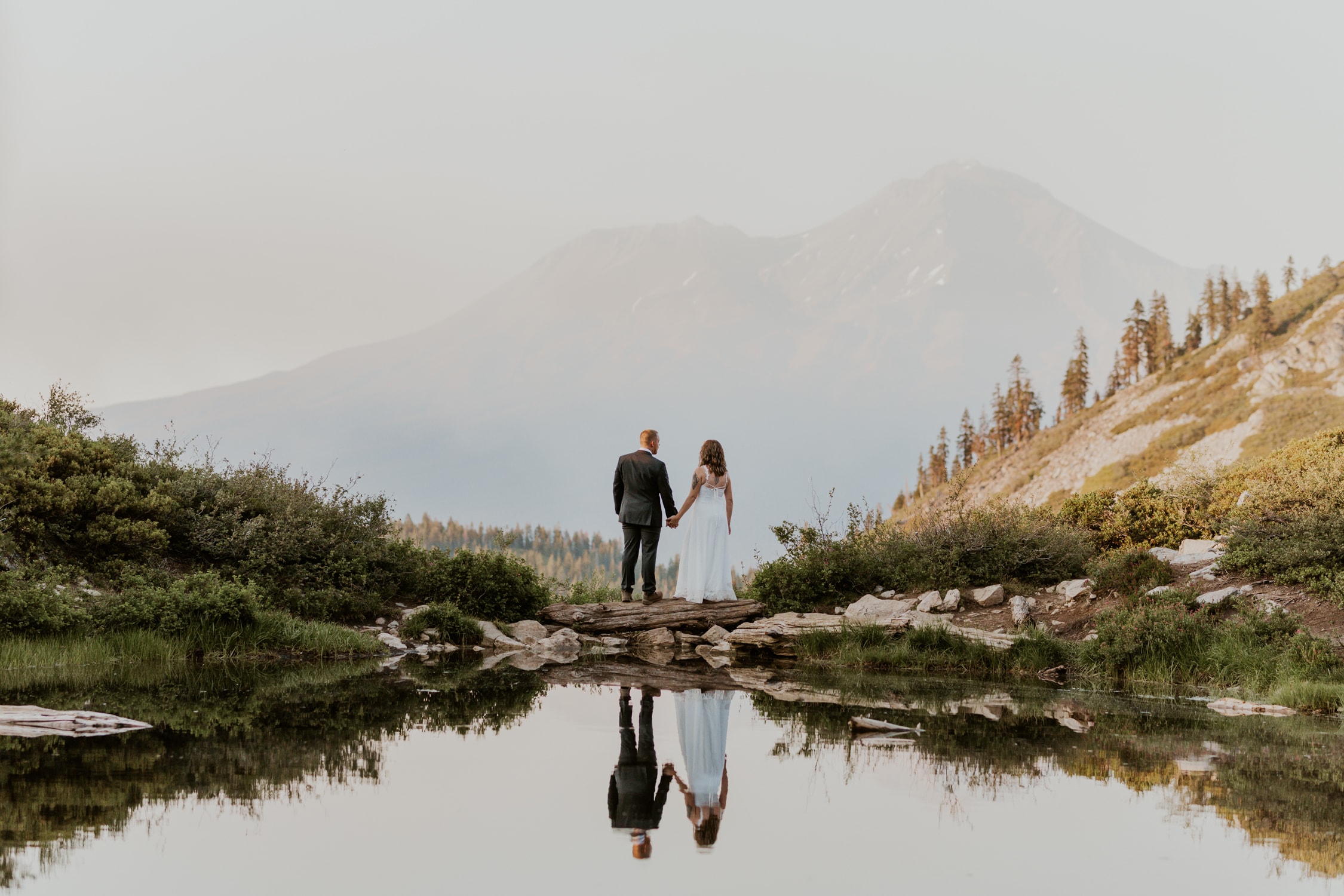 A couple holding hands in front of Mt. Shasta on their wedding day.