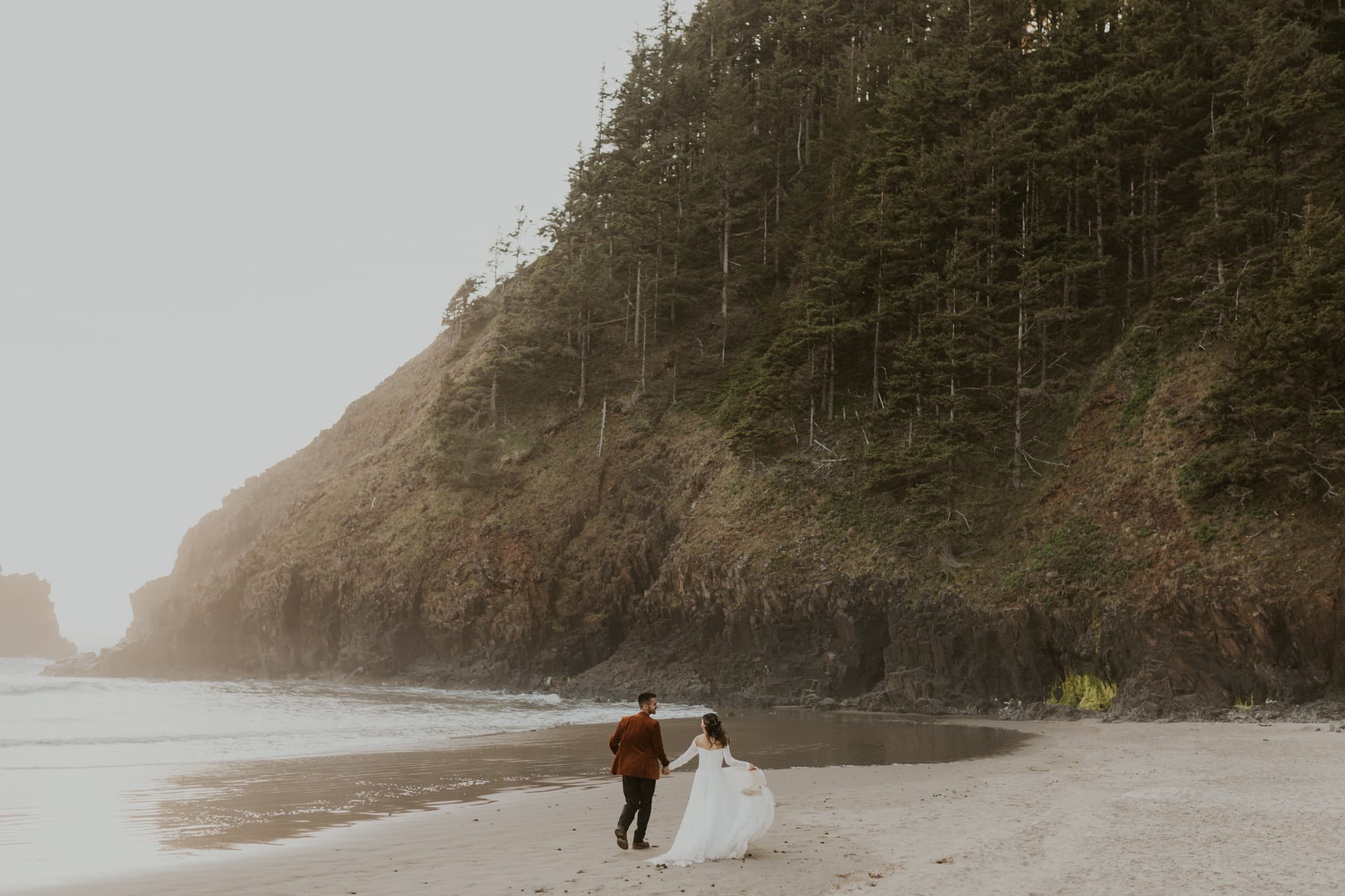A couple running on the beach in Oregon on their elopement day.