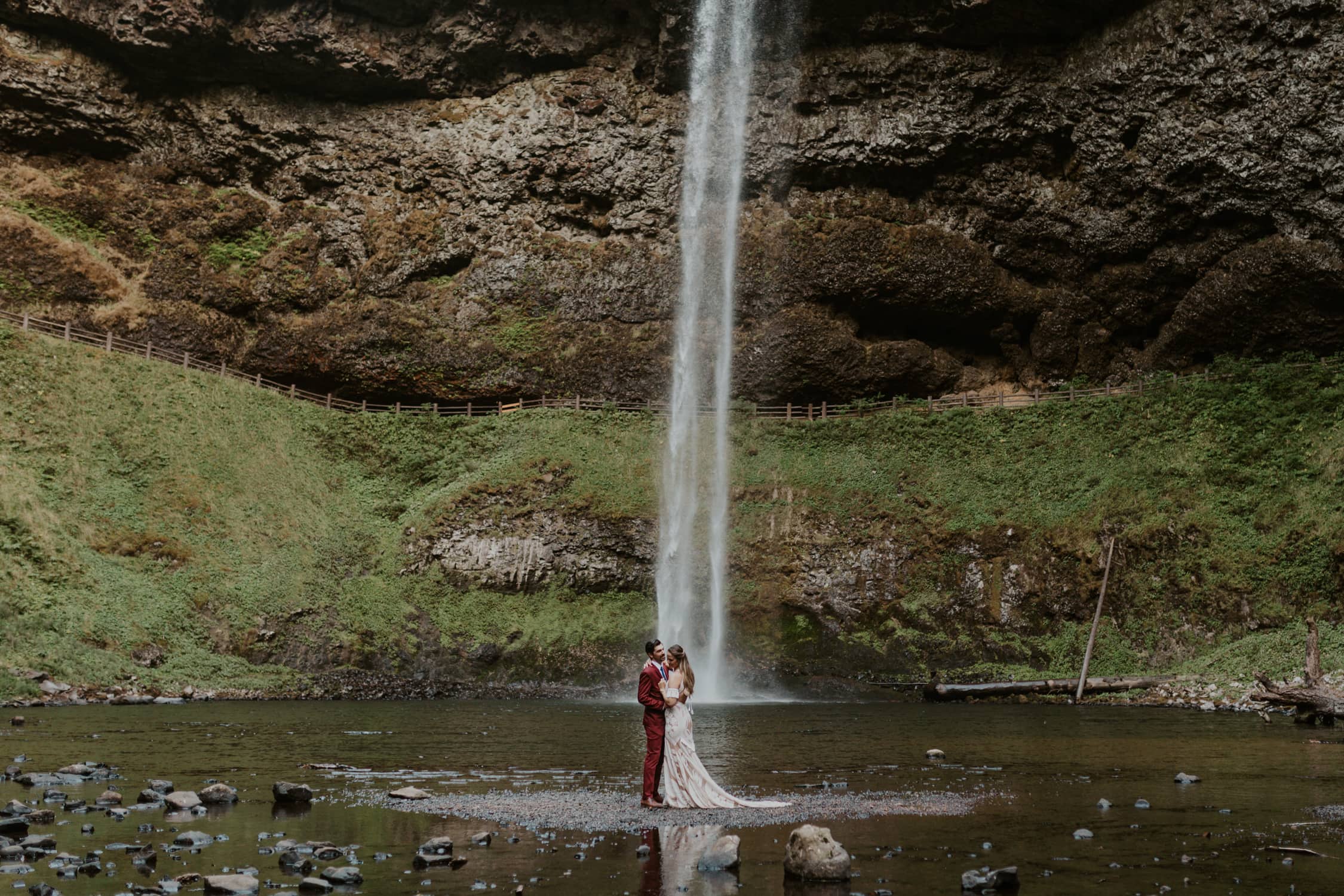 A couple hugging in front of a waterfall in Oregon.