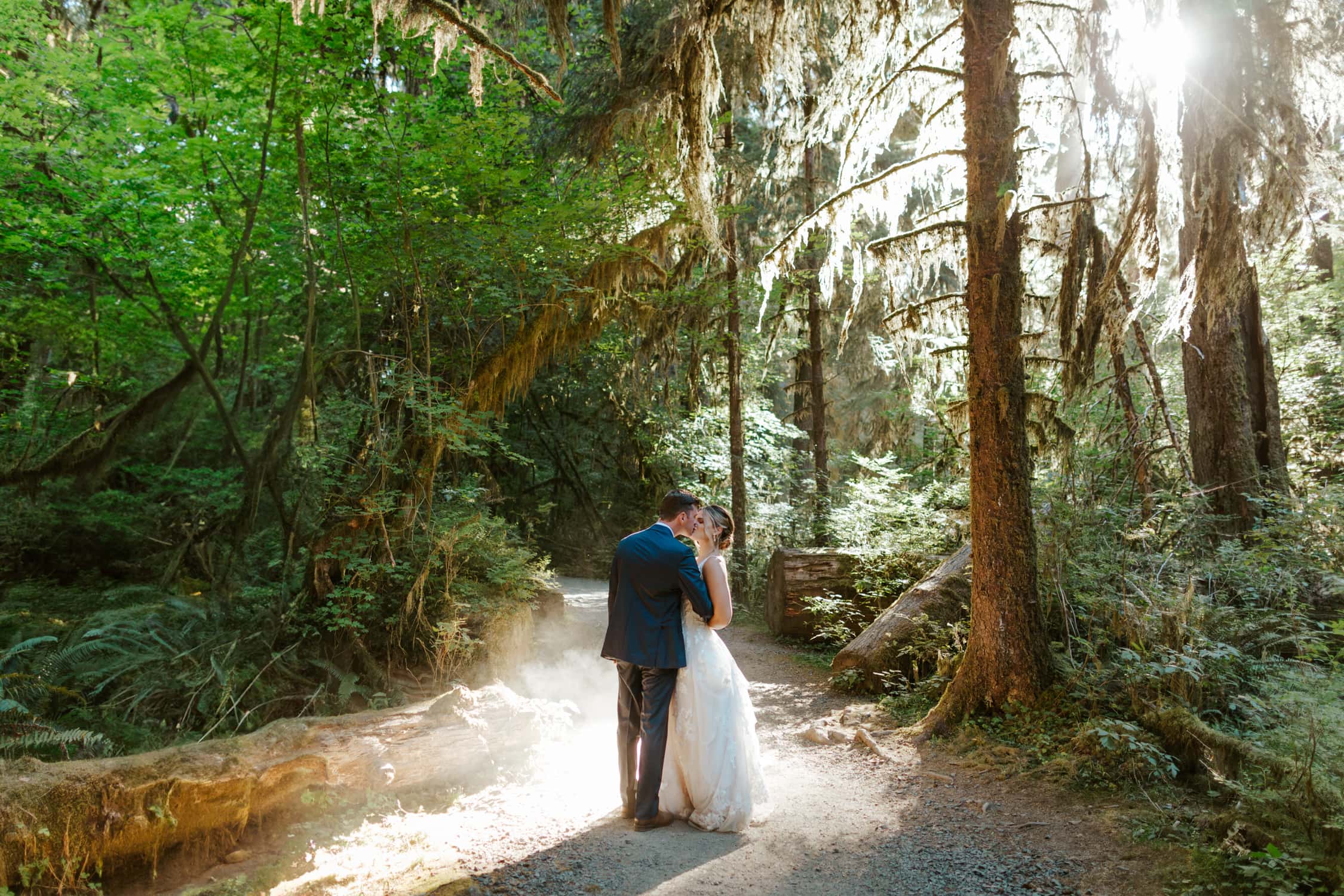 A couple in wedding attire kissing each other in the Hoh Rainforest.