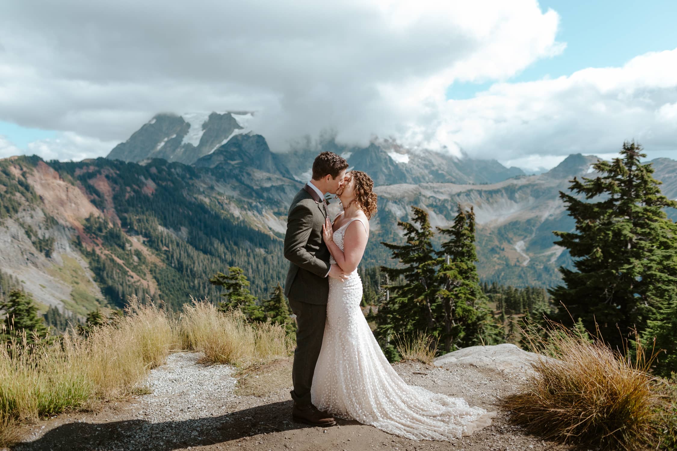 A couple in wedding attire having their first kiss at Artist Point in Washington State.