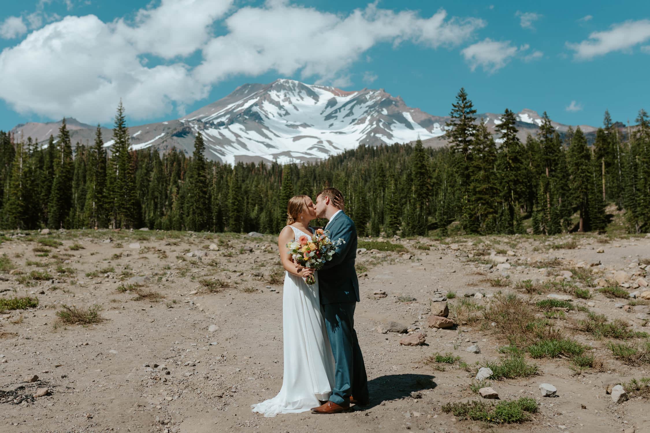 A bride and groom kissing in front of Mt. Shasta on their wedding day.