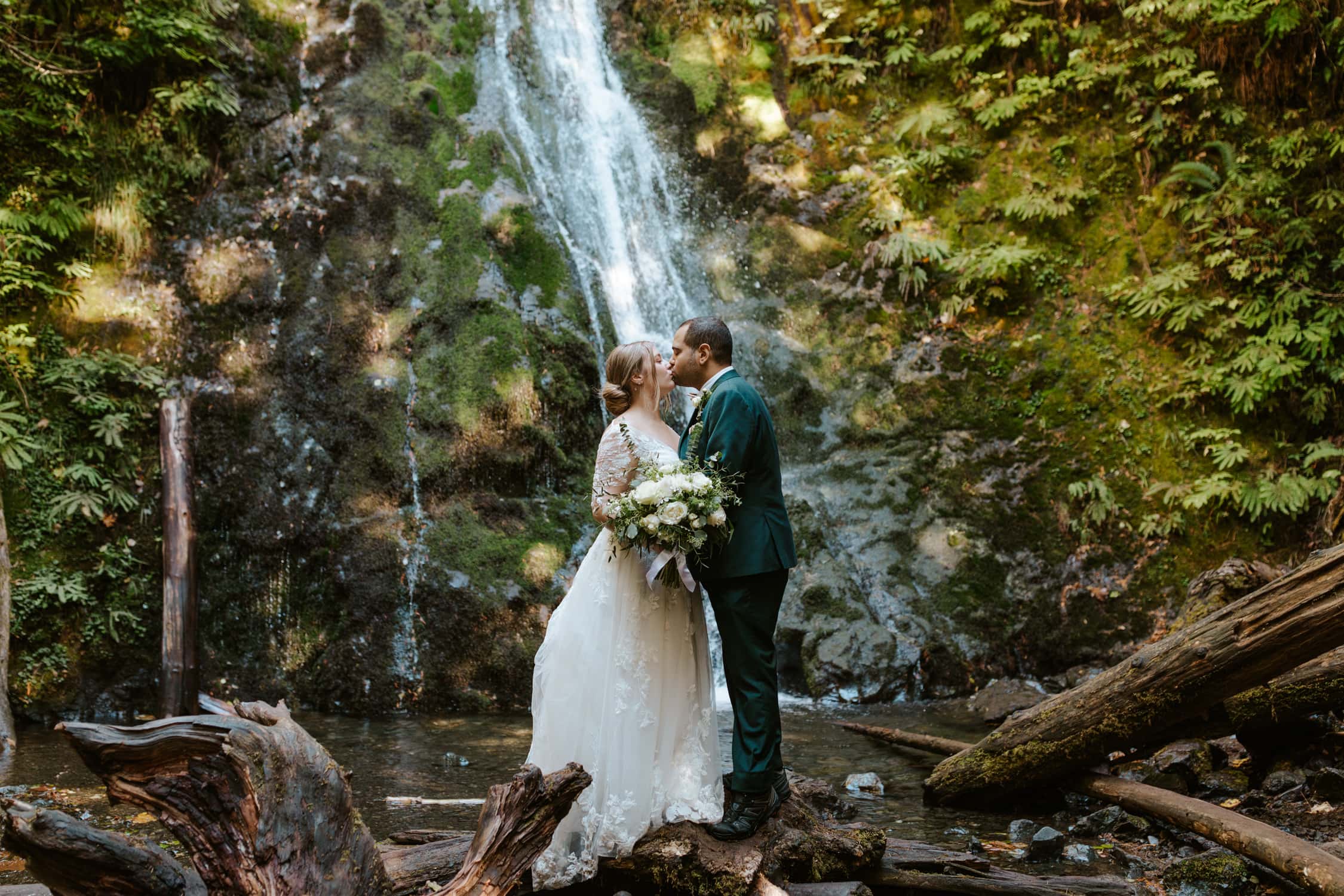 A bride and groom kissing in front of Madison Falls in Olympic National Park.